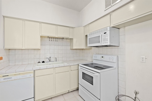 kitchen featuring sink, tasteful backsplash, tile countertops, white appliances, and light tile patterned floors