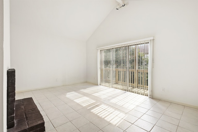 spare room featuring high vaulted ceiling and light tile patterned flooring