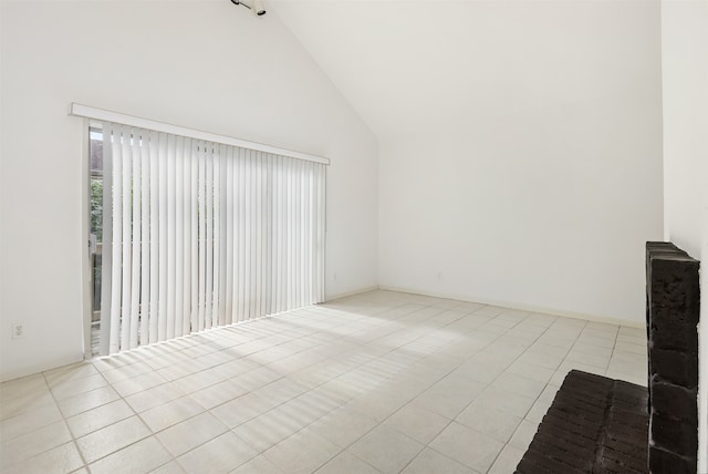 empty room with high vaulted ceiling and light tile patterned floors