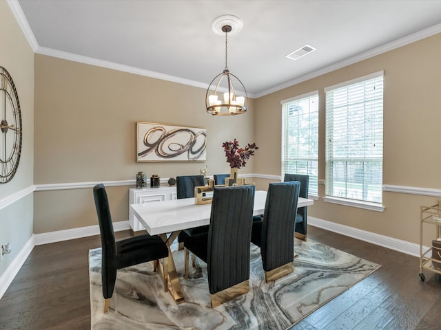 dining room with crown molding, dark hardwood / wood-style floors, and an inviting chandelier