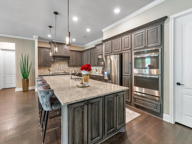 kitchen featuring a center island with sink, light stone countertops, dark hardwood / wood-style flooring, dark brown cabinetry, and stainless steel appliances