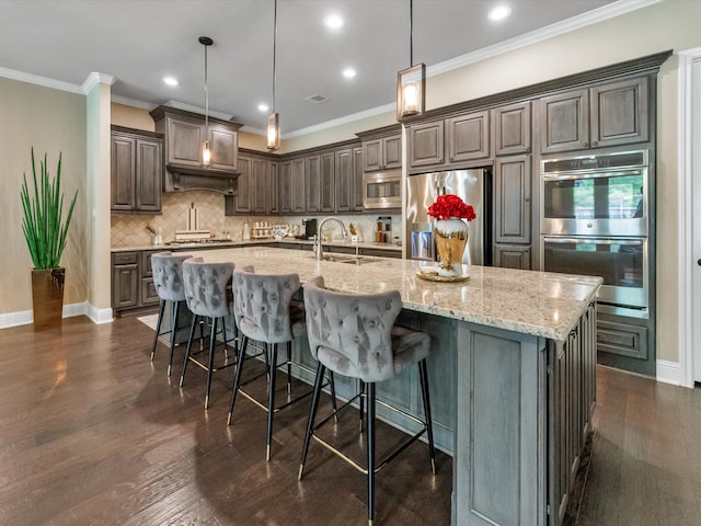 kitchen with a large island with sink, stainless steel appliances, dark hardwood / wood-style floors, and sink