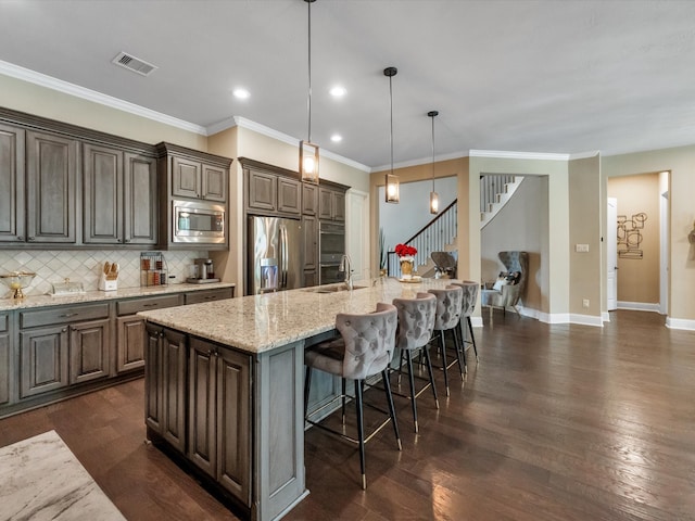 kitchen with stainless steel appliances, dark hardwood / wood-style floors, pendant lighting, a breakfast bar area, and a center island with sink