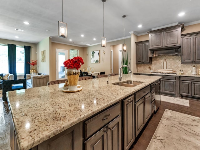 kitchen featuring a large island with sink, sink, light stone countertops, dark hardwood / wood-style flooring, and dark brown cabinetry