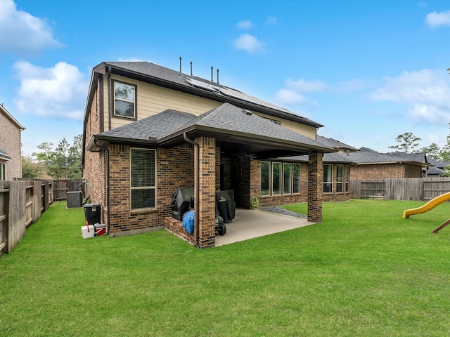 rear view of house with a patio area, a yard, and central AC