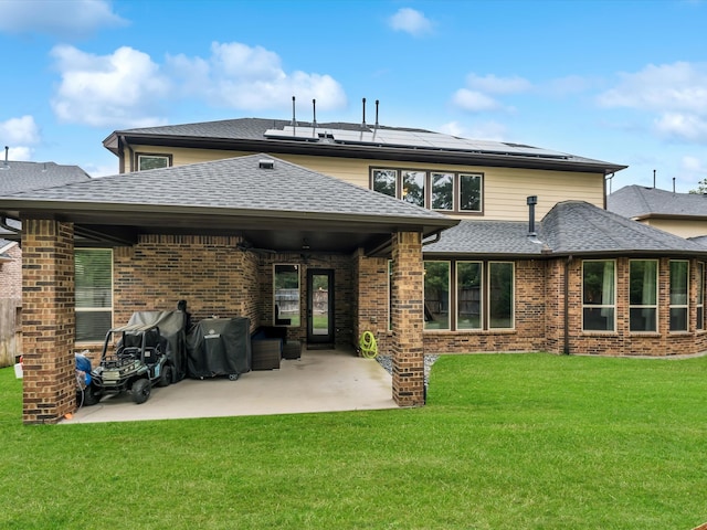 rear view of house featuring solar panels, a patio, and a lawn