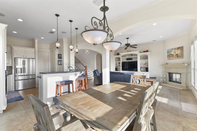 dining area featuring light tile patterned floors, ceiling fan, ornamental molding, and sink