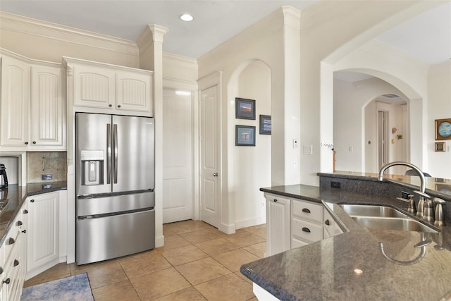 kitchen with stainless steel fridge, light tile patterned floors, white cabinetry, and sink