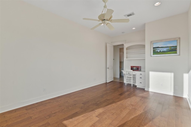 spare room with dark hardwood / wood-style floors, ceiling fan, and built in features