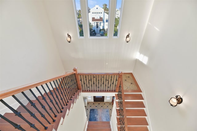 staircase featuring wood-type flooring and a high ceiling