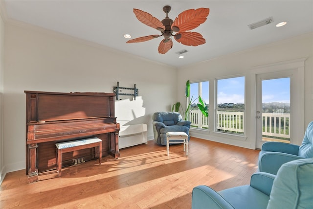 living area featuring ceiling fan, light wood-type flooring, and ornamental molding