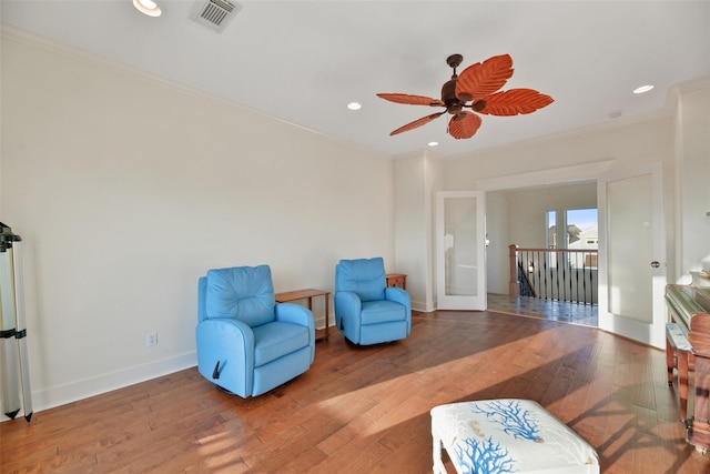 living area featuring ceiling fan, wood-type flooring, ornamental molding, and french doors