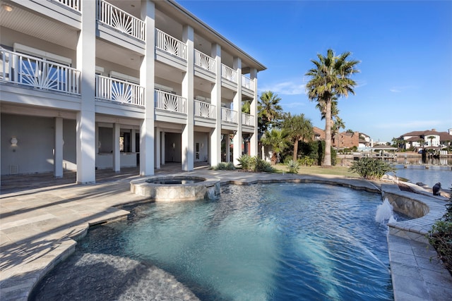 view of pool featuring an in ground hot tub, a water view, and a patio