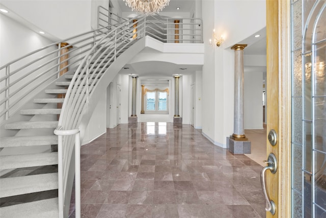 foyer entrance with decorative columns, a towering ceiling, and a chandelier