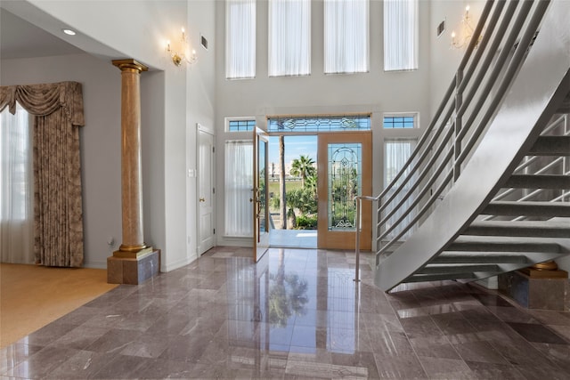 entrance foyer featuring decorative columns, french doors, and a towering ceiling