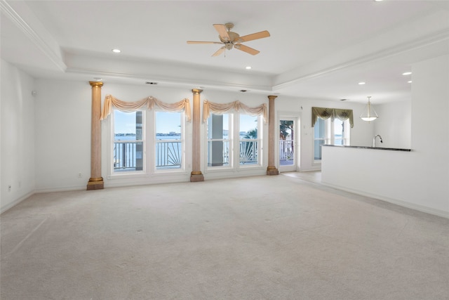 unfurnished living room featuring ceiling fan, a raised ceiling, ornamental molding, and light carpet