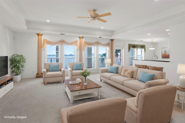 living room with light carpet, a water view, ceiling fan, ornamental molding, and a tray ceiling