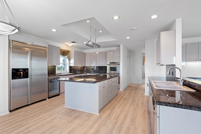 kitchen with sink, a center island, wine cooler, light hardwood / wood-style floors, and appliances with stainless steel finishes