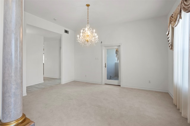 spare room with a notable chandelier and light colored carpet