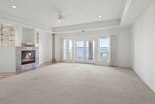 unfurnished living room featuring ceiling fan, a raised ceiling, a fireplace, and light carpet