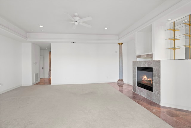 living room with a tray ceiling, a tile fireplace, ceiling fan, and carpet floors