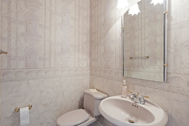 bathroom featuring toilet, sink, and tile walls