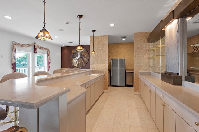 kitchen with sink, stainless steel fridge, tile walls, decorative light fixtures, and a breakfast bar area