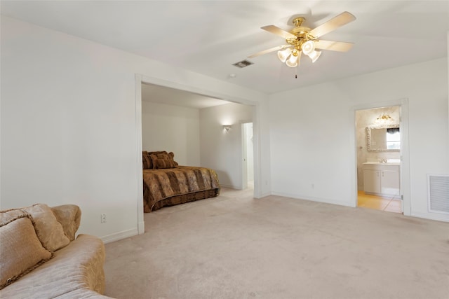 bedroom featuring light colored carpet, ceiling fan, and ensuite bathroom