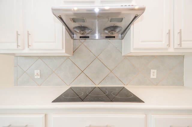 kitchen featuring black electric stovetop, decorative backsplash, white cabinetry, and exhaust hood