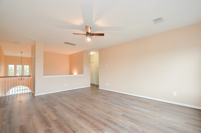 unfurnished room with hardwood / wood-style floors and ceiling fan with notable chandelier