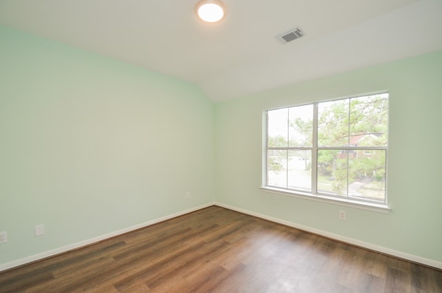 empty room with dark hardwood / wood-style flooring and vaulted ceiling