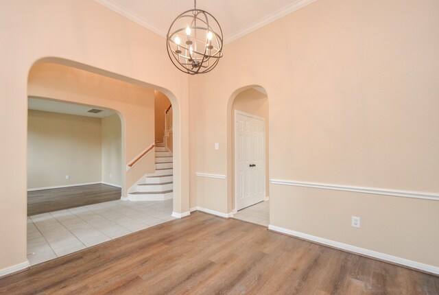 empty room featuring a high ceiling, an inviting chandelier, light hardwood / wood-style flooring, and ornamental molding