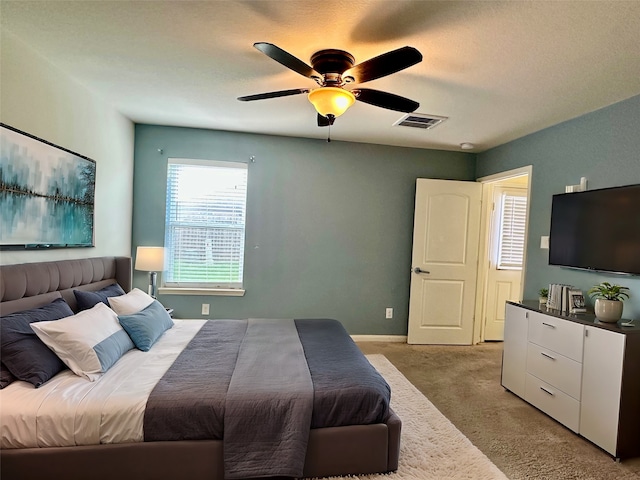 bedroom with ceiling fan, light carpet, and a textured ceiling