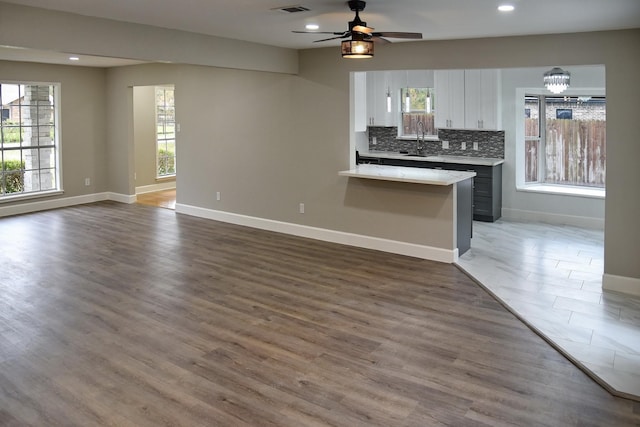 kitchen with backsplash, ceiling fan, sink, white cabinets, and hardwood / wood-style floors