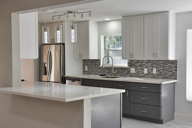 kitchen with hanging light fixtures, sink, gray cabinets, appliances with stainless steel finishes, and kitchen peninsula