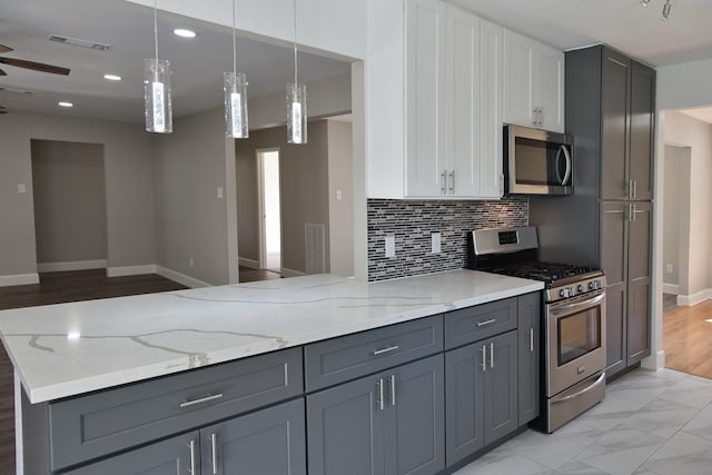 kitchen featuring pendant lighting, gray cabinetry, white cabinets, light stone countertops, and stainless steel appliances