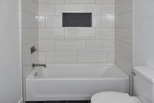 bathroom featuring toilet and tiled shower / bath