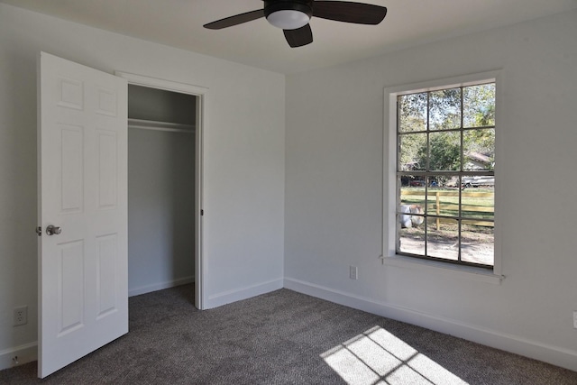 unfurnished bedroom featuring dark colored carpet, a closet, and ceiling fan