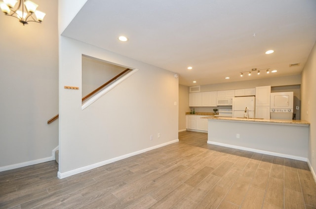 unfurnished living room featuring light wood-type flooring, sink, and an inviting chandelier