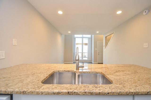 kitchen with light stone counters, lofted ceiling, and sink