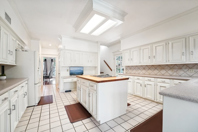 kitchen with stainless steel gas stovetop, white cabinets, ornamental molding, and a kitchen island