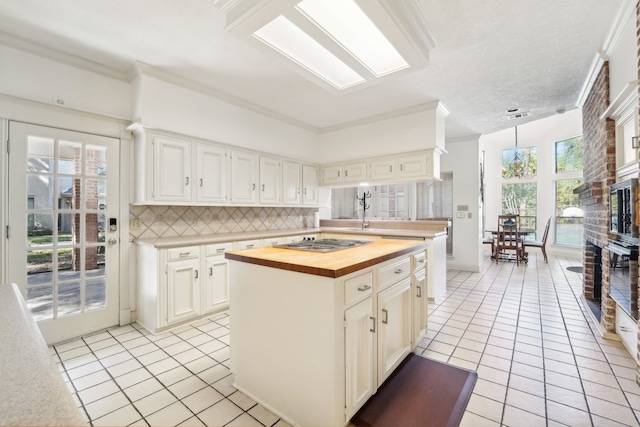 kitchen with butcher block countertops, a center island, white cabinets, and plenty of natural light