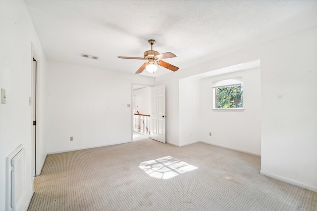 carpeted empty room featuring ceiling fan and a textured ceiling