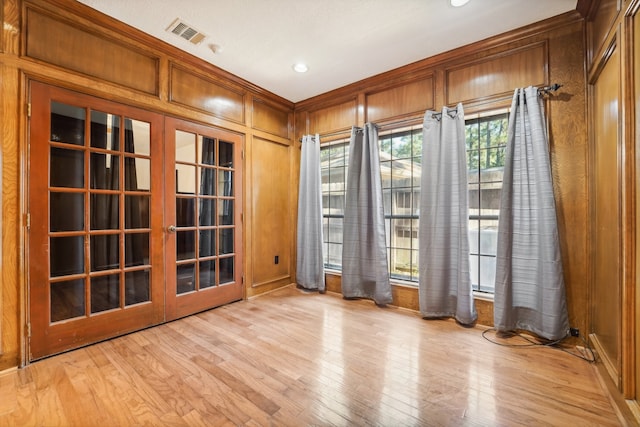 unfurnished room featuring wood walls, french doors, and light hardwood / wood-style flooring