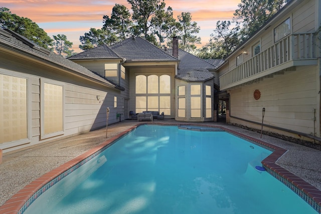 pool at dusk with a patio area