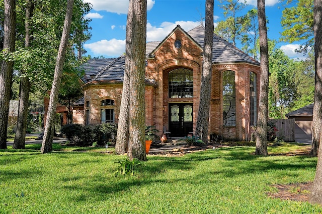 english style home featuring french doors and a front lawn