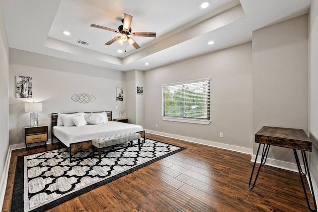 bedroom featuring a raised ceiling, ceiling fan, and dark wood-type flooring