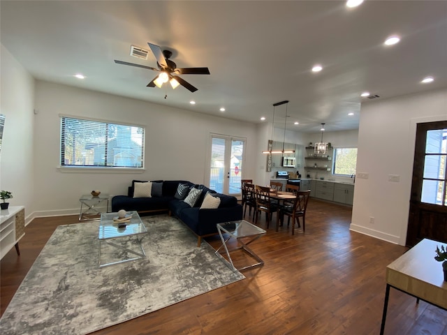 living room with dark wood-type flooring, ceiling fan, and a healthy amount of sunlight