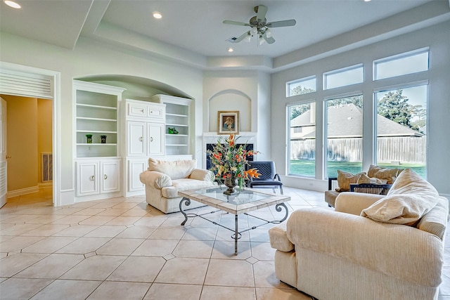 tiled living room with built in shelves and ceiling fan