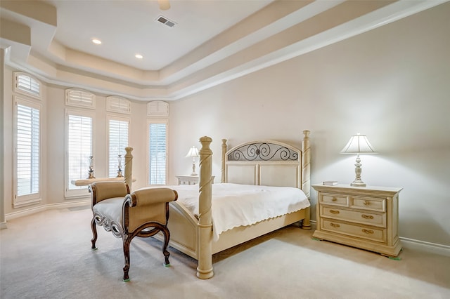 carpeted bedroom with ornamental molding and a tray ceiling